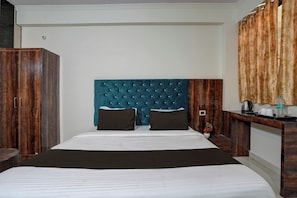 Una habitación de hotel con una cama grande, un armario de madera, un escritorio de madera y un espejo.