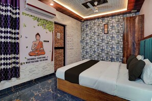 A room with a bed, a wall with a Buddha mural, a calendar, and a patterned wall. - Hotel O Swastik Inn (Lucknow)