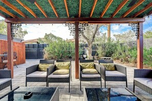 En uteplats med flätade möbler och en pergola.