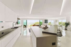 A modern kitchen with a large island, a dining area with a view, and a balcony overlooking the ocean. - Penthouse w/ Ocean View, Oceania 331 by Bocobay (Noord)