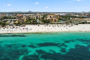 A coastal resort with a beach, clear turquoise waters, and a backdrop of buildings. - Penthouse w/ Ocean View, Oceania 331 by Bocobay (Noord)