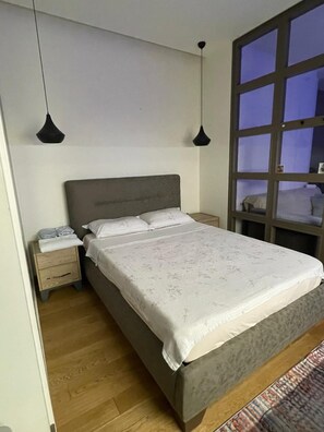 A bedroom with a bed, bedside tables, and a window with a view. - İzmir’in kalbinde ışık şölenine hazır mısınız? (İzmir)