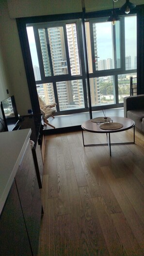 A modern living room with a large window, a round coffee table, and a sofa. - İzmir’in kalbinde ışık şölenine hazır mısınız? (İzmir)
