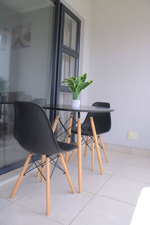 A modern dining area with a glass table and black chairs with wooden legs. - Beautiful View With Netflix and Fast Wifi (Johannesburg)