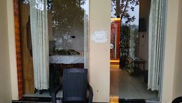 Una habitación con una cama, una silla y un ventanal corredera que da a un área exterior.