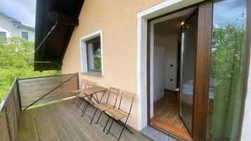 A balcony with wooden furniture and a glass door leading to an interior space.