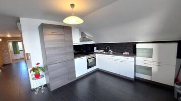 A modern kitchen with white cabinetry, a black countertop, and a built-in oven.