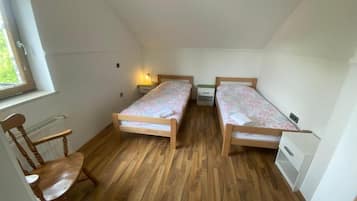Acomodação pequena, com um único quarto, duas camas de madeira, uma cadeira e um radiador.