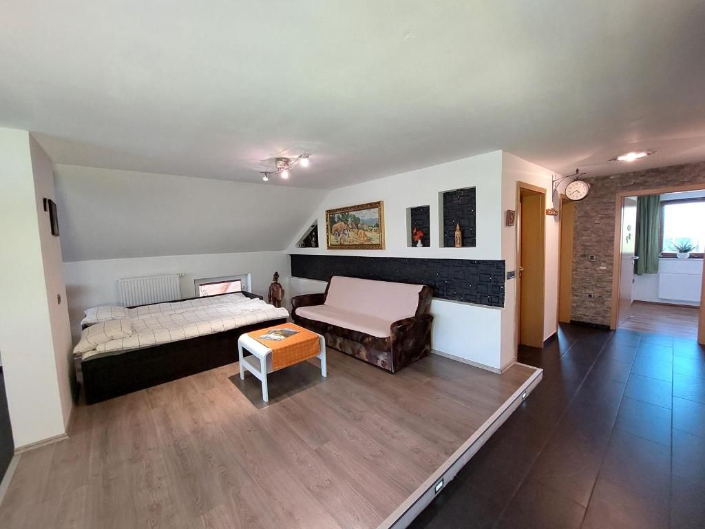 Quarto moderno com cama, sofá, mesinha e um quadro na parede.