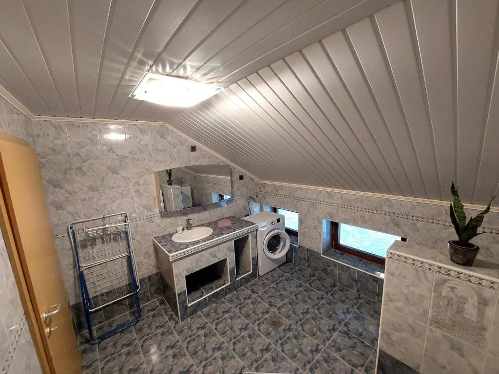 A compact bathroom with a sink, mirror, and washing machine.