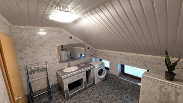 A compact bathroom with a sink, mirror, and washing machine.