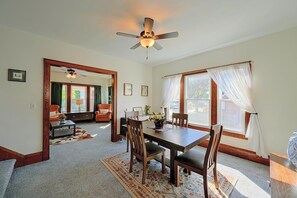 A dining area with a wooden table, chairs, and a ceiling fan. There is a window with curtains and a view of the outside. - Walkable Canton Duplex Near Fairgrounds & Dtwn! (Canton)