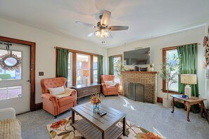 A living room with a fireplace, a ceiling fan, and a television. - Walkable Canton Duplex Near Fairgrounds & Dtwn! (Canton)