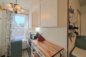 A compact kitchen with a wooden countertop, a built-in microwave, and a hanging pot rack. - Walkable Canton Duplex Near Fairgrounds & Dtwn! (Canton)
