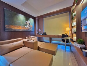 Een moderne woonkamer met een grote bank, een bureau met een laptop en een televisie.