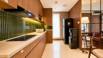 Cozinha moderna com armários de madeira, geladeira preta e área de refeições com cadeiras e mesa de madeira.