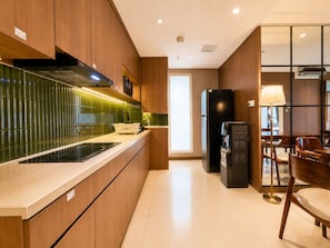 Una cocina moderna con armarios de madera, un refrigerador negro y un comedor con sillas y mesa de madera.