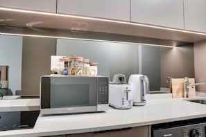 Een moderne keuken met een ingebouwde magnetron, broodrooster en koffiezetapparaat.