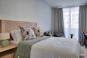 Een hotelkamer met een bed, bureau, stoel en raam met gordijnen.