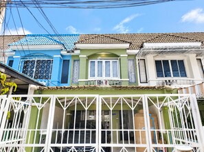 A residential building with a green facade, multiple windows, and a white gate. - Charming 2-bedroom House Rental in Muang Pattaya (Pattaya)