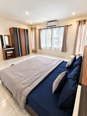 A modern bedroom with a large bed, a desk, and a window with curtains. - Charming 2-bedroom House Rental in Muang Pattaya (Pattaya)