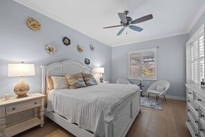 A bedroom with a bed, nightstands, a chair, a dresser, a ceiling fan, and wall art. - Spacious Naples Vacation Home | Sunshine & Relaxation (Lely Resort)