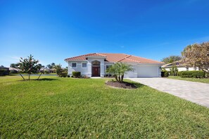 A single-story house with a red-tiled roof, a front porch, and a well-maintained lawn. - Spacious Naples Vacation Home | Sunshine & Relaxation (Lely Resort)