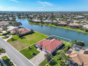 An aerial view of a residential area with houses, a lake, and a clear sky. - Spacious Naples Vacation Home | Sunshine & Relaxation (Lely Resort)