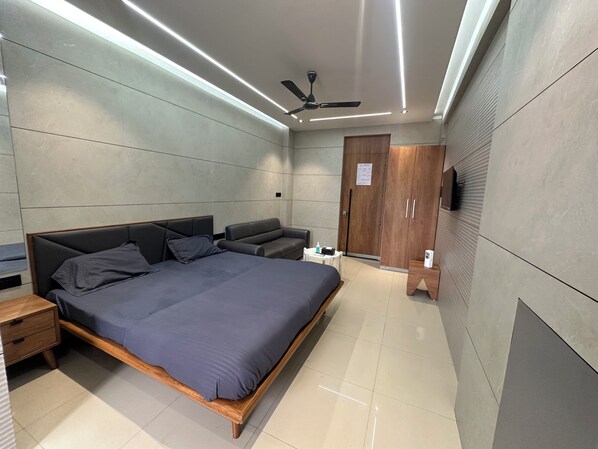 A modern bedroom with a bed, bedside tables, a seating area, and a wardrobe.