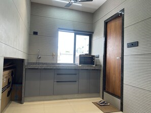 A kitchen with a built-in microwave, a window, and a door.