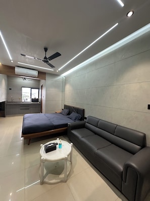 A modern bedroom with a bed, sofa, and a small table with items on it.