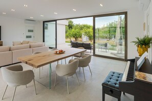 A modern living space with a dining area, a piano, and a view of the outdoors. - Stunning villa with private pool in Taormina - DiCasaInSicilia (Taormina)