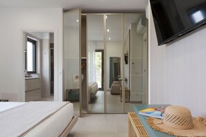 A bedroom with a bed, a TV, a wardrobe, and a bathroom visible through a glass door. - Stunning villa with private pool in Taormina - DiCasaInSicilia (Taormina)