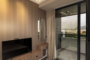 Ein modernes Schlafzimmer mit Fernseher, Holzvertäfelung, einem Spiegel, einer Schiebeglasdoor und Blick auf die Stadt.