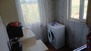 A compact laundry room with a washing machine, a drying rack, and a window with a view of the outdoors. - MORNING GLOW LOGDE - HOLLIDAY HOUSE - ISSOLATED FORM EVERITHING-7 MIN FROM TELAV (Telavi)
