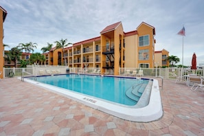 A hotel pool with a clear blue water surface, surrounded by a tiled deck. - Bayside Bliss | First-Floor Condo with Water Views (St. Pete Beach)