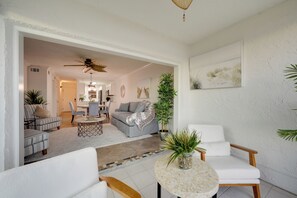 A modern living room with a sofa, chairs, a coffee table, and a dining area in the background. - Bayside Bliss | First-Floor Condo with Water Views (St. Pete Beach)