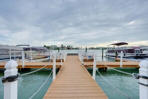 A wooden pier leading to a marina with boats docked on either side. - Bayside Bliss | First-Floor Condo with Water Views (St. Pete Beach)
