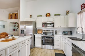 A modern kitchen with white cabinetry, stainless steel appliances, and a central island. - Private Pool Oasis | Fiber Wi-Fi | Near Stadium (Peoria)
