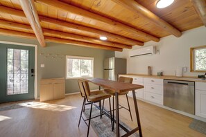 A modern kitchen with wooden beams, a dining area with bar stools, a refrigerator, and a dishwasher. - Cozy Prescott Cabin, Surrounded By Ponderosa Pines (Prescott)