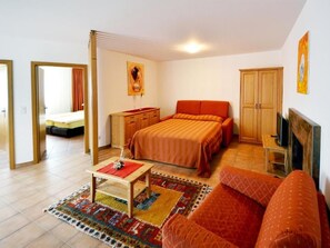 Um quarto com cama, sofá, escrivaninha e guarda-roupa.