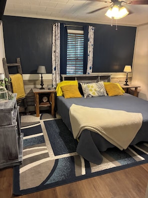 A bedroom with a bed, nightstands, a lamp, a window with curtains, a ceiling fan, and a wooden ladder. - 3-bedroom house within walking distance to shopping, eats , church, schools (Kaplan)
