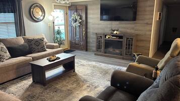 A living room with a sofa, a coffee table, a television, and a fireplace.