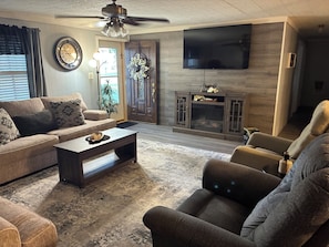 A living room with a sofa, a coffee table, a television, and a fireplace. - 3-bedroom house within walking distance to shopping, eats , church, schools (Kaplan)