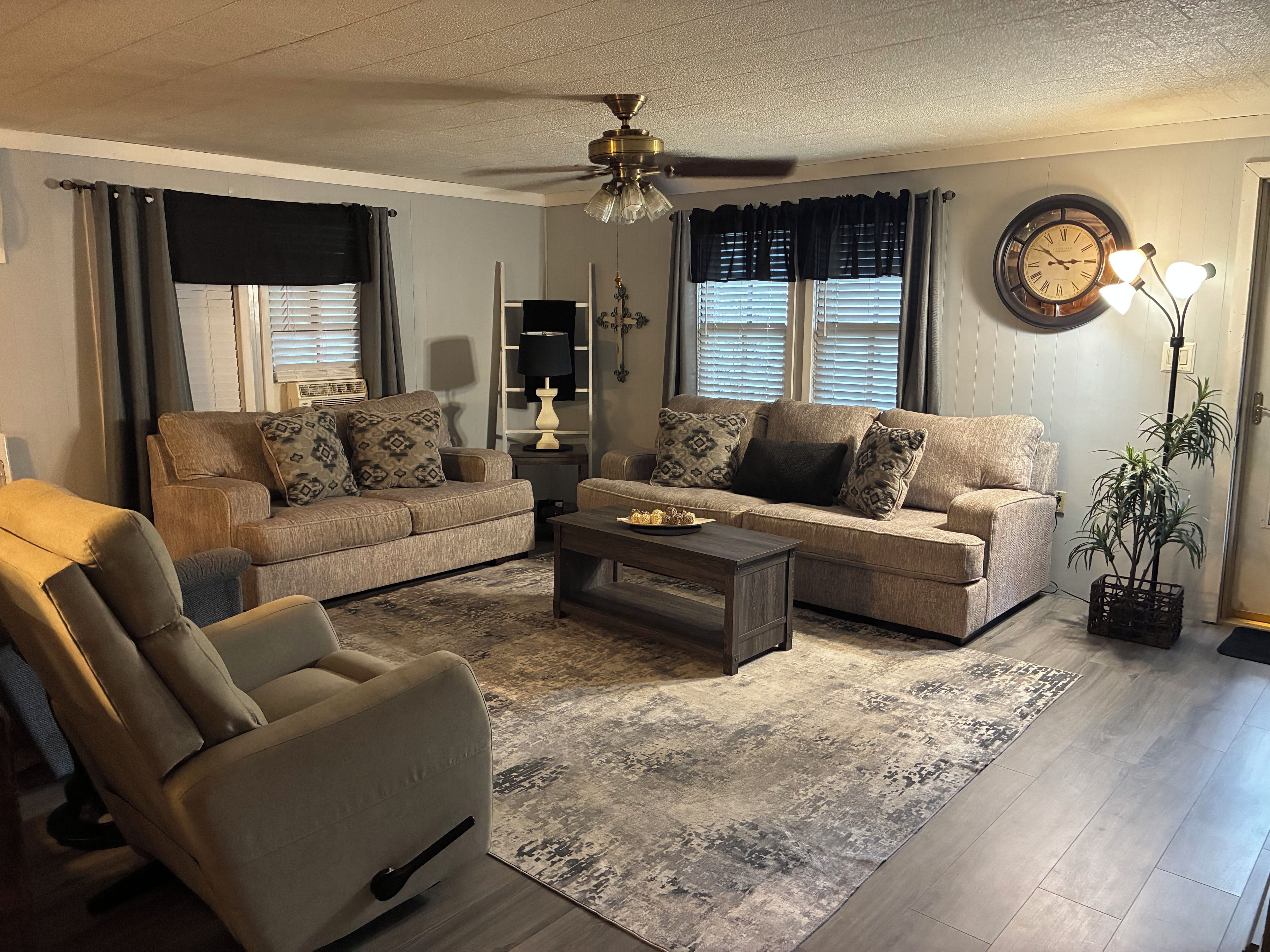 A living room with a sofa, armchair, coffee table, and a potted plant.