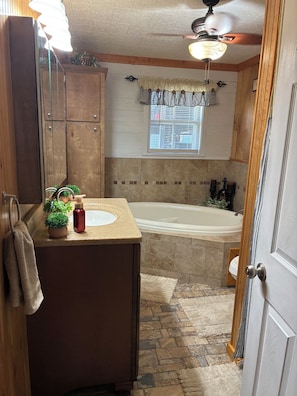 A bathroom with a bathtub, a vanity with a mirror, and a window with curtains. - 3-bedroom house within walking distance to shopping, eats , church, schools (Kaplan)
