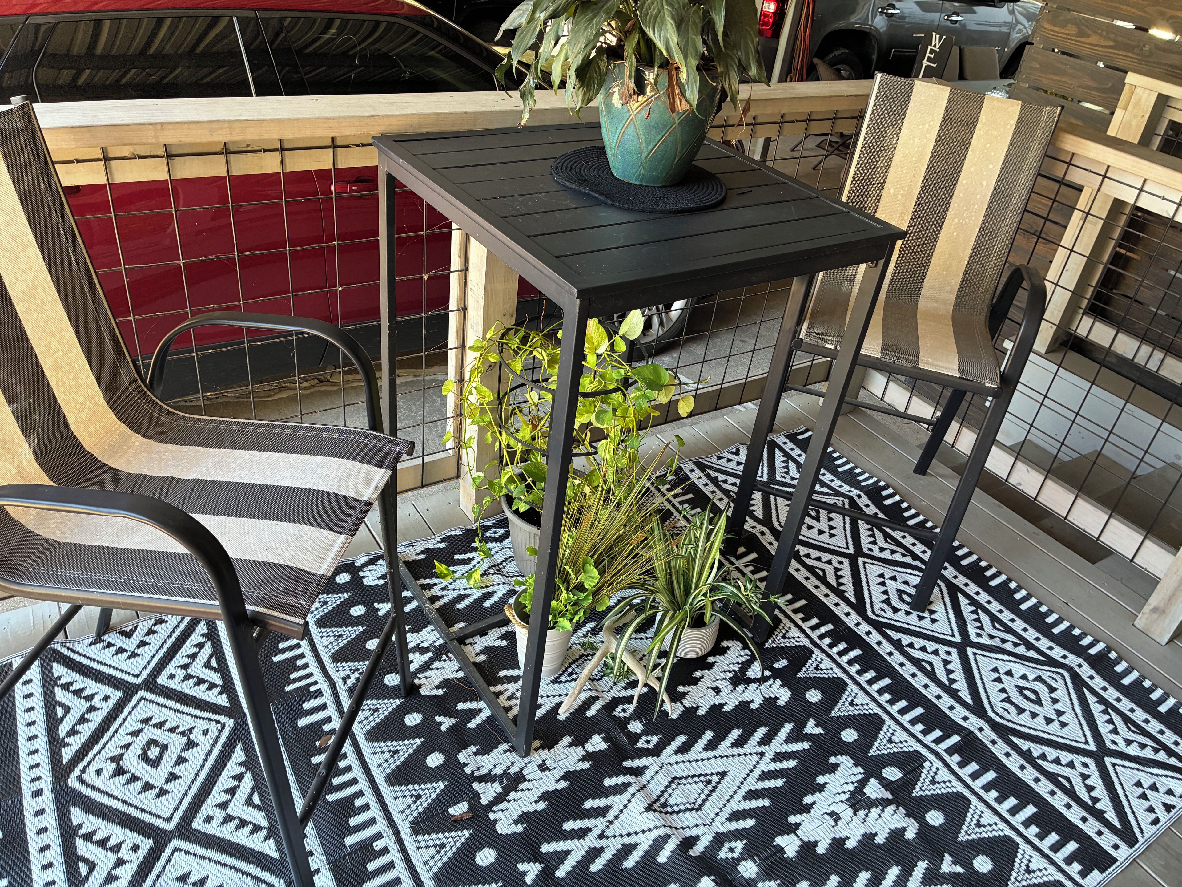 Eine Terrasse mit Tisch, Stühlen und Blumentöpfen.