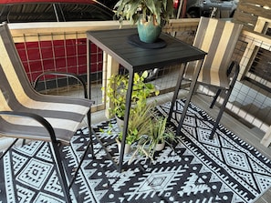Eine Terrasse mit Tisch, Stühlen und Blumentöpfen.