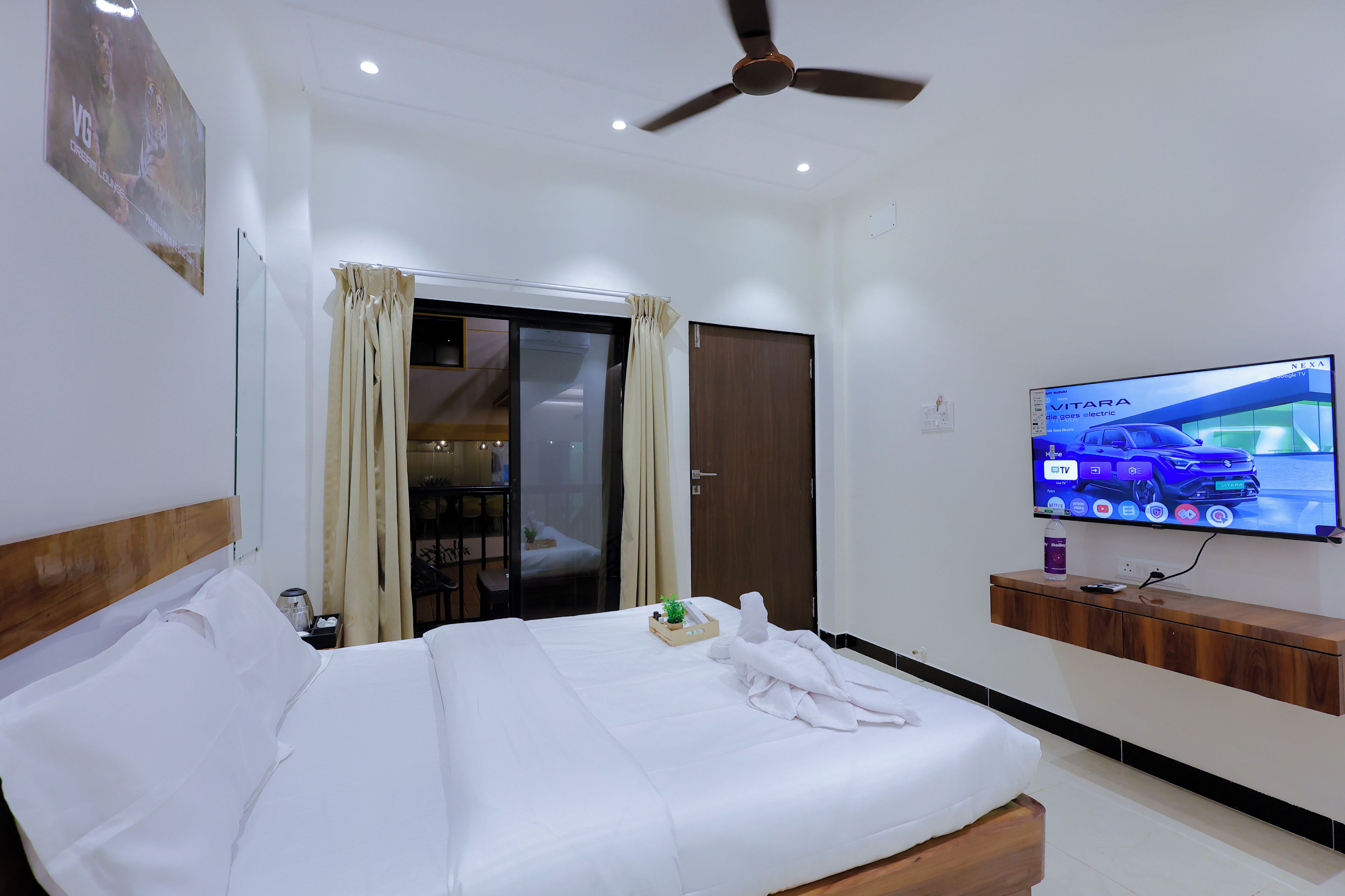 Une chambre d’hôtel avec un lit, une télévision, un ventilateur de plafond et une vue sur l’extérieur.