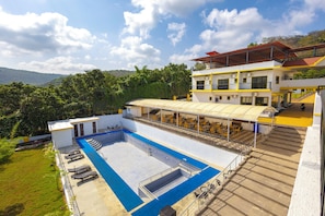 A hotel with a swimming pool, outdoor seating, and a view of the surrounding greenery. - Coastal Cliff by ILIF Hotels (Murud)